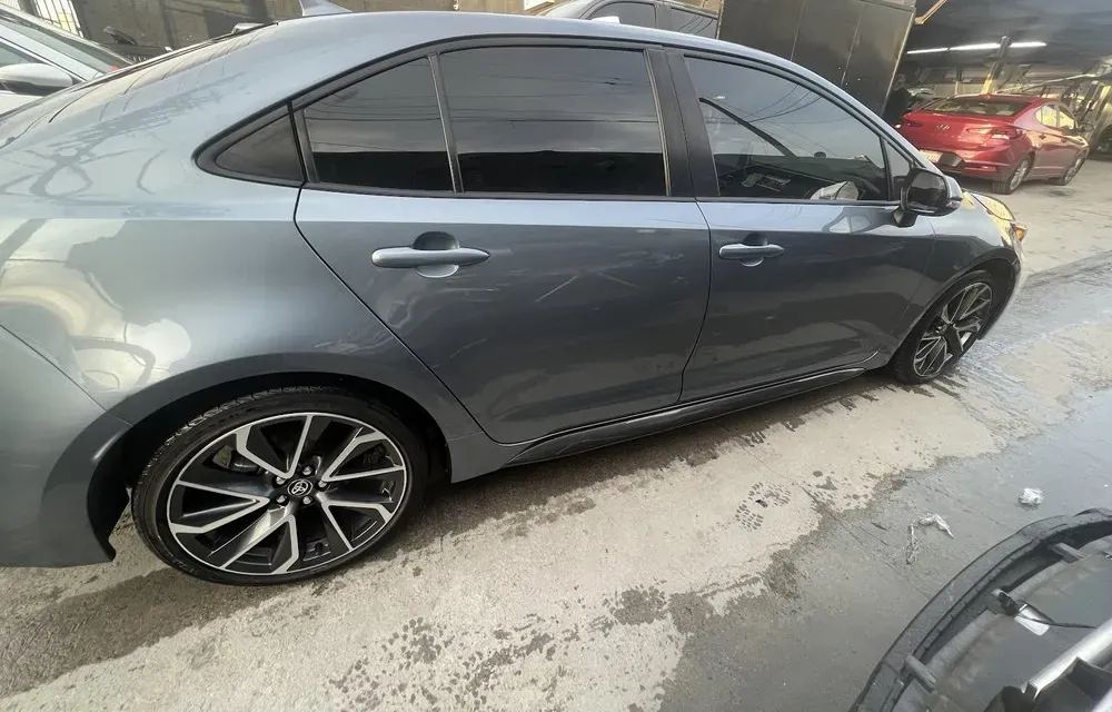 Gray Toyota Corolla sedan parked on the wet floor inside the On Point Auto Body shop