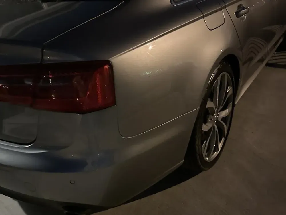 Rear quarter panel and taillight of a silver Audi sedan at dusk